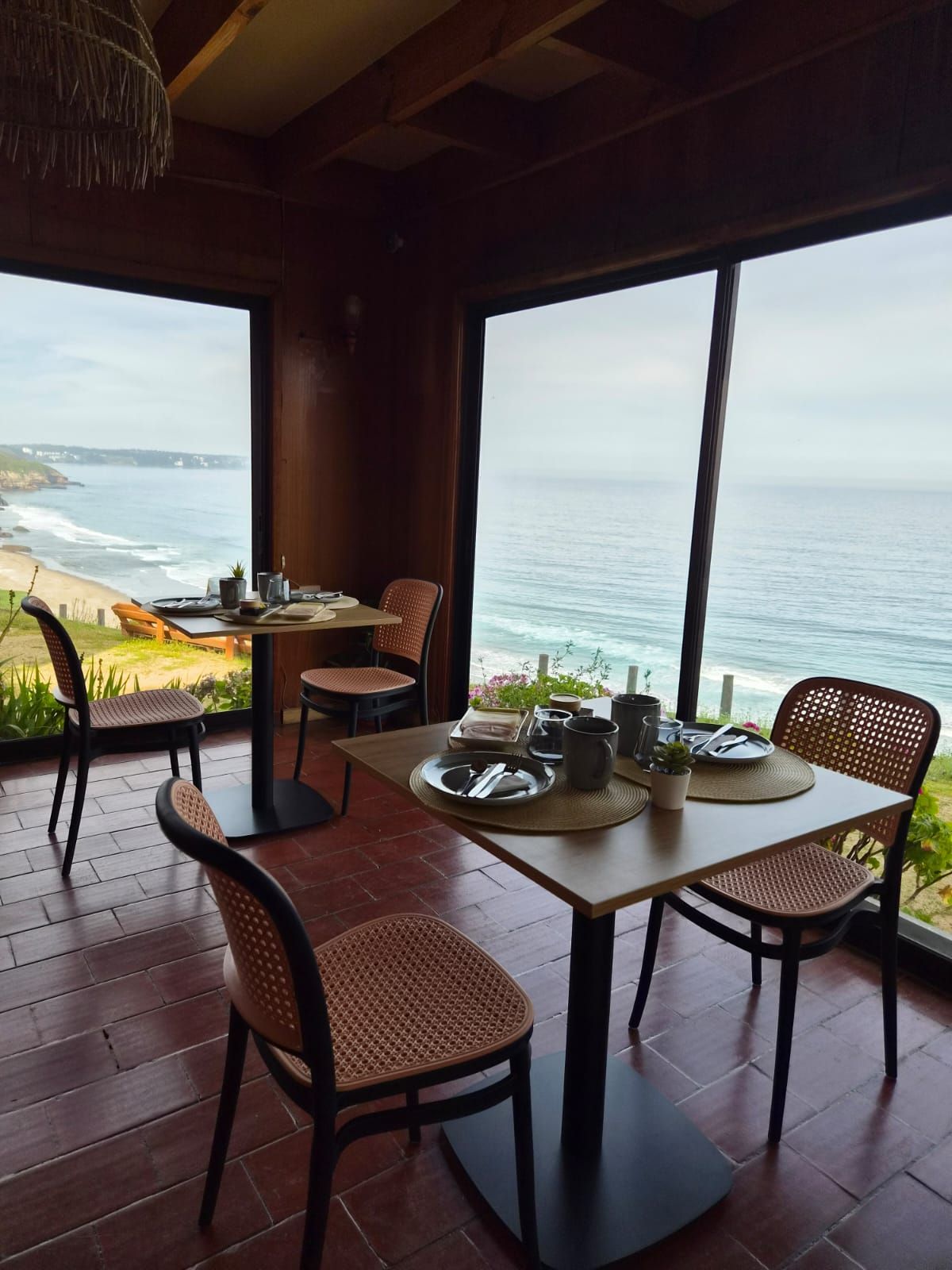 Mesas del comedor junto a ventanales con vista a la playa de Aguas Blancas