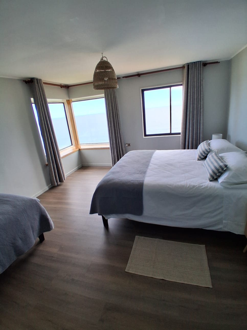 Suite Deluxe: cama king frente a los ventanales en esquina hacia el Pacífico